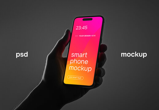 A hand holding a smartphone in a dark studio setting &ndash; mockup