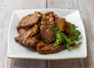 Spicy Sliced Taiwanese Beef with savory sauce, sesame seeds and cilantro served in plate on Wood Table Close up Side view of Hong Kong food