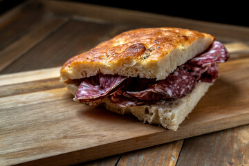 Rustic salami sandwich with crispy focaccia on a wooden board