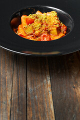 Gourmet pasta with cherry tomatoes and crispy topping served in a black plate