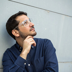 Thinking Man Wearing Safety Glasses in a Neutral Background
