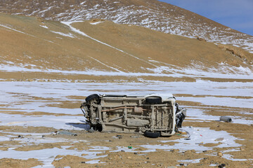 An overturned car on beside road snowing day