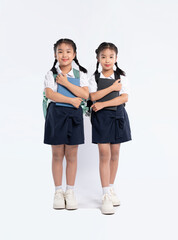 Obraz premium Two young students pose with their books and backpacks, ready for school, in matching uniforms.