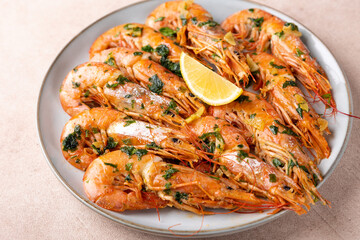 Langoustines fried in butter with garlic and parsley. Served with a slice of lemon. Traditional Mediterranean cuisine. A popular appetizer in restaurants and pubs. Homemade cooking. Selective focus.