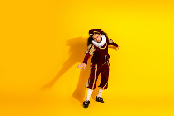 Young man dressed as a nobleman in classic medieval fashion on a vibrant yellow background
