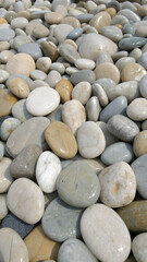 Smooth pebbles on beach, natural colors and textures, vertical close-up, phone wallpaper