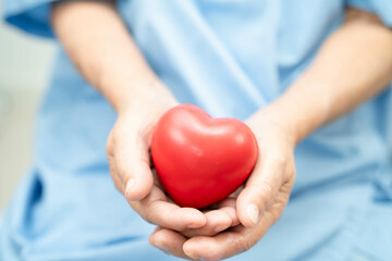 Asian elder senior woman patient holding red heart in hospital.