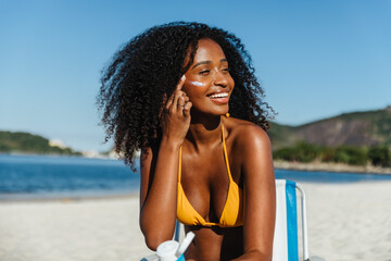 Smiling woman applying SPF sunscreen for protection on a summer day at the beach