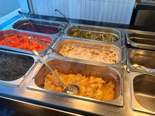 Hot food counter in a cafeteria with staff-served meals ready for customers