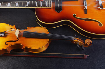 Jazz guitar and violin with a bow on a dark background. © yrafoto