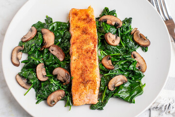 seasoned salmon resting on  spinach and mushrooms