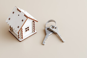 A house with keys on a beige background. A place to copy. The concept of real estate transactions.