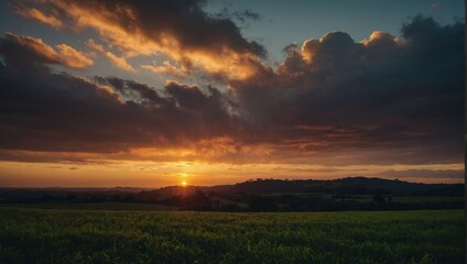 Dramatic Sunset Over a Rolling Landscape with Golden Clouds and a Field of Green