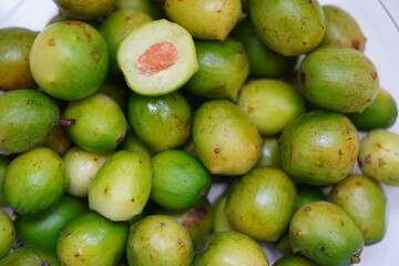 Green and ripe umbu fruit (Spondias tuberosa), also known as Brazil plum. A fruit cut open in...