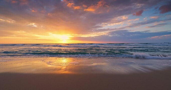 Golden summer sunset over the ocean waves crashing on the sea shore and sand of a tranquil tropical beach