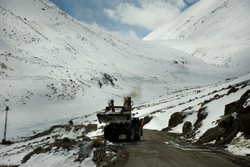 Indian and tibetan people work use machinery move clearing snow covered out of road at Khardung La...