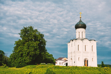 White Orthodox church with golden cross under dramatic sky