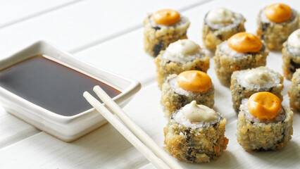 Crispy sushi rolls with spicy sauces and soy sauce on a white surface, ideal for restaurant menus, culinary promotions, cooking blogs, or food ads. Photo.