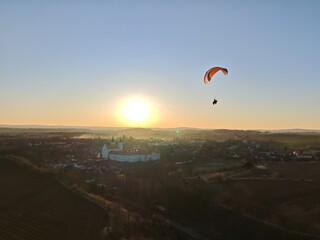 Aerial view of powered paraglider flying over mountainous landscape and forests, concept of adventure sports and aerial freedom