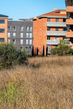 Urban residential area with modern apartments and natural landscape. A contrast between contemporary living spaces and undeveloped land, symbolizing urban expansion.