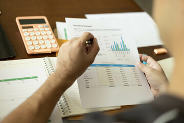 the businessman is sitting at a desk with a calculator and a stack of papers. She is looking at the...