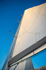 Sunlit top piece of a sail of a sailing yacht in the wind sailing on the sea 