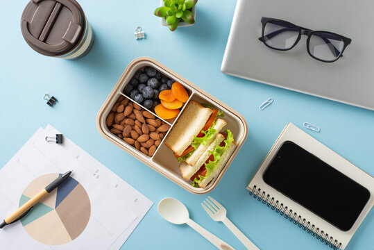 Balanced lunch of fruits, nuts, and sandwiches with office accessories and a laptop on desk
