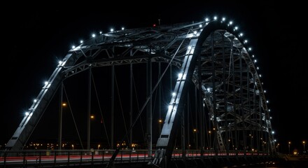 Obraz premium Illuminated Steel Arch Bridge at Night - A majestic steel arch bridge, brilliantly illuminated at night, stands against a dark sky. Light trails from passing vehicles add dynamism to the scene