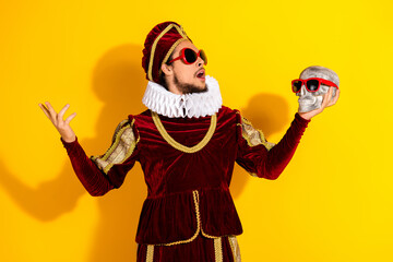 Young nobleman in classic medieval attire with humorous modern sunglasses posing against vibrant...