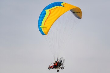 Two thrill-seekers pilot a powered paraglider across a cloudy sky, embracing freedom and adventure...