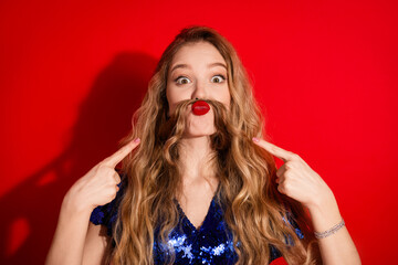 Naklejka premium Young Woman Making a Playful Pose with Hair for a Comical Gesture on Red Background