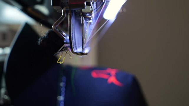 Machine embroidery of a black hat. Embroidering a design with red thread shot out of focus close up. Concept for: Automated work, Embroidery machine, Thread, Fabric, Needle, Hat. 4k video 50fps.