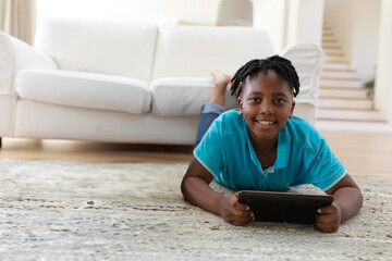 Smiling child using tablet on living room floor, enjoying leisure time at home, copy space