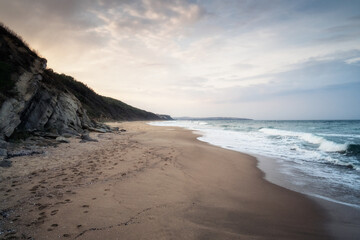 Sunset view of a picturesque beach with a long and empty sandy strip with footsteps and gentle sea waves on the Black Sea coast, Bulgaria.