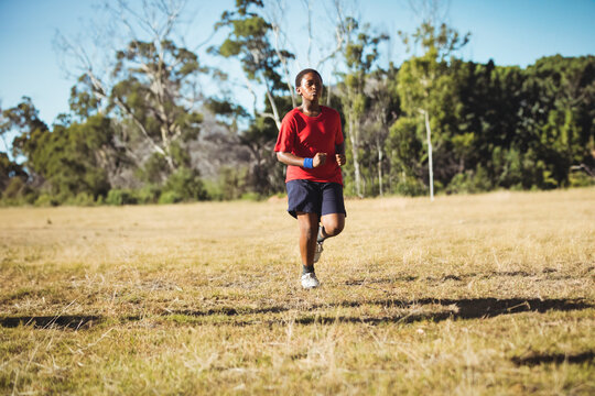 Young boy running outdoors on grassy field, enjoying fitness boot camp activity, copy space
