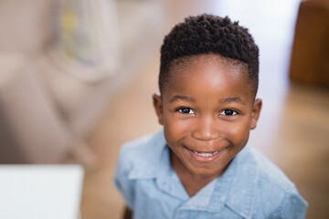 Smiling young boy at home, wearing blue shirt, looking at camera happily