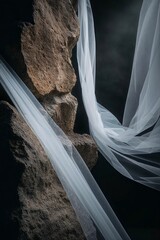 Translucent fabric draped over textured rocks in a dramatic and artistic composition