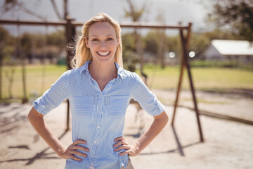 Smiling teacher standing confidently on playground, enjoying sunny day at school