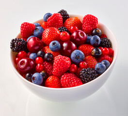 Beerenmischung in weisser Porzellanschale, Himbeeren, Blaubeeren, Kirschen, 