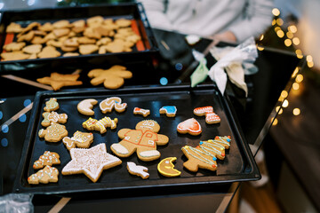 Gingerbread cookies with colorful ornaments lie on a baking sheet on the table
