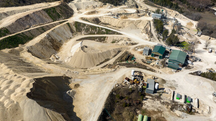 Aerial view of a sand and gravel quarry. There are industrial vehicles at work.