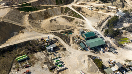 Aerial view of a sand and gravel quarry. There are industrial vehicles at work.
