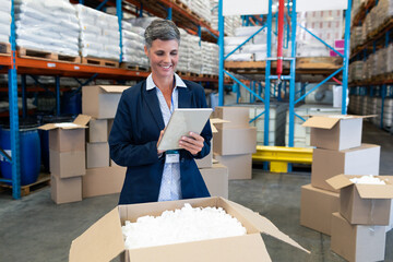 Warehouse manager using tablet while checking inventory in large storage facility, copy space