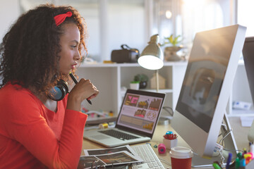 Creative woman working at desk with computer and laptop, focusing on design, copy space