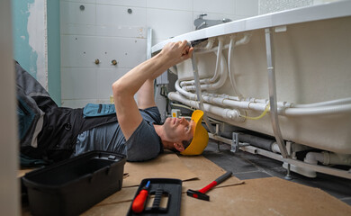 Man servicing the pipe system of a bathtub with hydromassage.