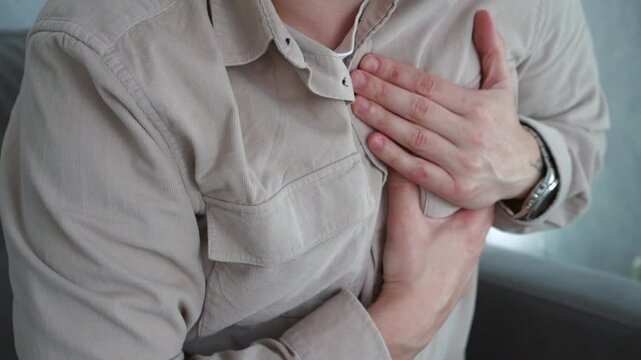 A man suffers from severe chest pain.
Heart pain.
A young man has a heart attack on the couch.
A man needs medical help because of severe heart pain.