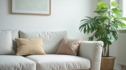 A light-colored sofa adorned with two decorative pillows sits in a bright room, complemented by a lush indoor plant. Sunlight filters through a nearby window.