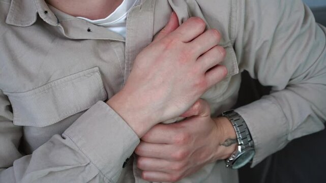 A young man in a light shirt experiences pain in the heart due to severe stress.
Heart attack and panic attack.
Health problems of the guy