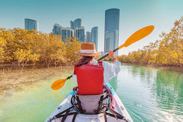 Woman paddling in kayak exploring mangrove park in Abu Dhabi, United Arab Emirates
