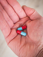 A pair of blue and red pills in the palm of a hand - take your medicine
